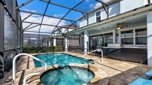 A pool area with a hot tub, a bar, and a covered patio with a view of the sky. - Solara Sunshine (Kissimmee)