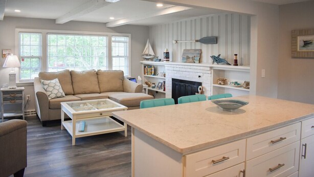 Een moderne woonkamer met een beige bank, een glazen salontafel en teal stoelen.