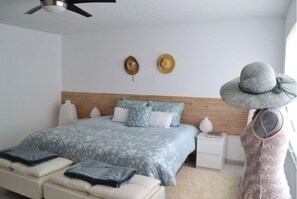 Relax in this serene bedroom with a large bed, bedside tables, and a ceiling fan.