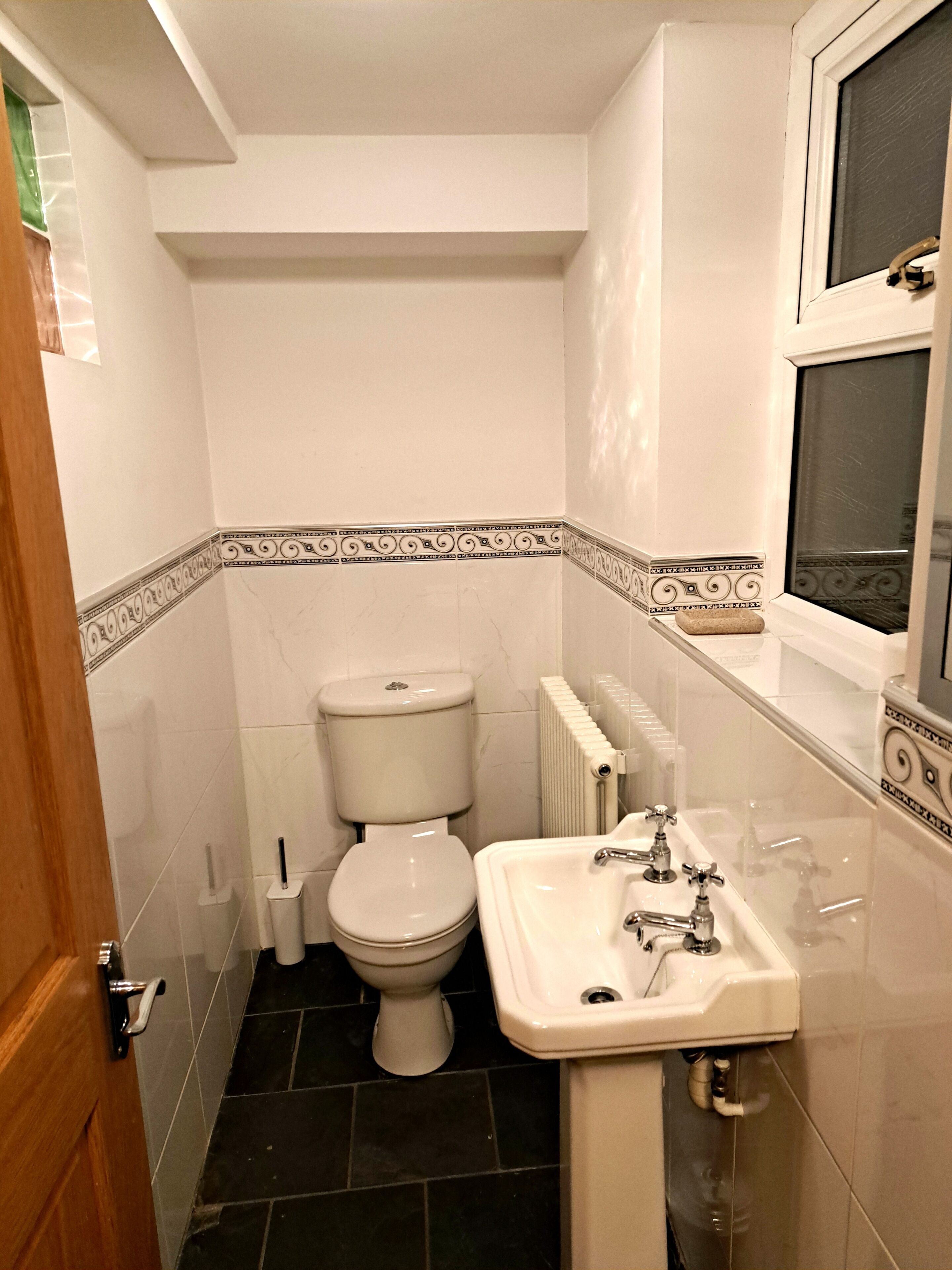 A compact bathroom with a toilet, sink, and radiator.