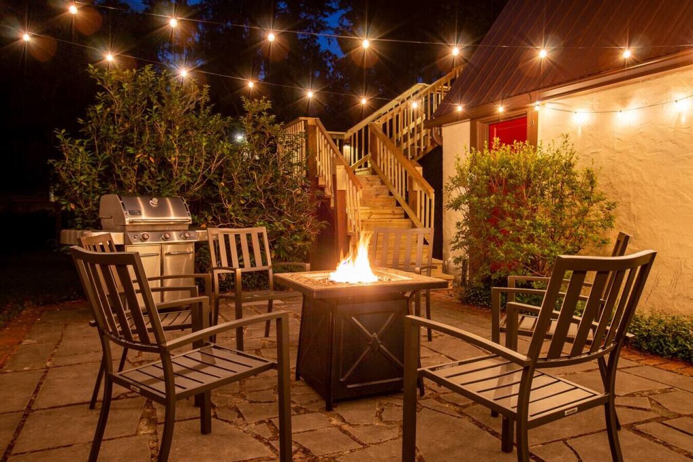 Une terrasse extérieure avec un barbecue, un foyer et des chaises en bois.