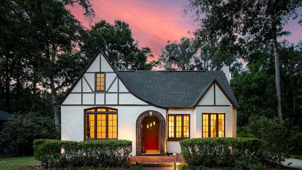 A Tudor-style house with a steeply pitched roof, symmetrical facade, and a central entrance with a red door. - Walk to UF Stadium! Fabulous Chic Historic Home (Gainesville)
