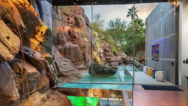 A modern interior with a glass wall, a rock formation, and a pool. - Camelback Vista - 4BR Luxury Estate w/ Infinity Pool & Camelback Views (Phoenix)