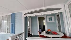 Ein überdachter Wintergarten mit Tisch und Stühlen, einem kleinen Fenster und einer Tür zu einem Innenraum.