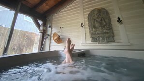 Un jacuzzi con techo de madera y una estatua de Buda en la pared.