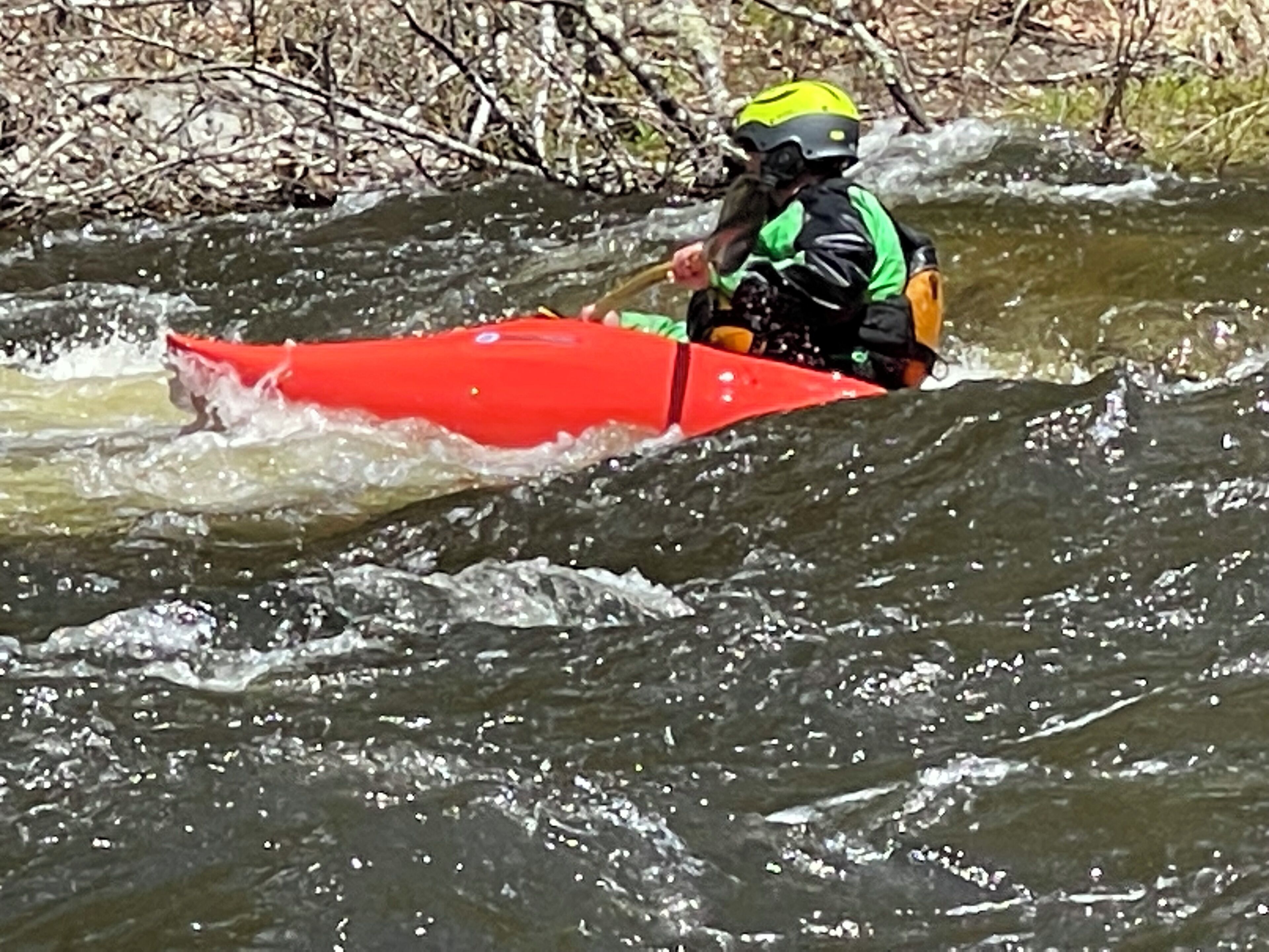 Una persona en un kayak rojo recorriendo un río.