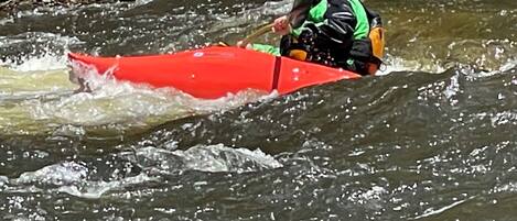 Una persona en un kayak rojo recorriendo un río.