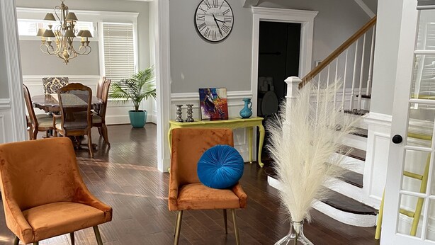 Un salón comedor espacioso con piso de madera, una zona de estar y una escalera que conduce a otro nivel.