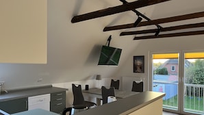 Una cocina moderna con comedor, televisor montado en la pared y vistas al exterior.