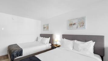 Una habitación de hotel con dos camas individuales, una mesita de noche con lámpara y obras de arte en las paredes.