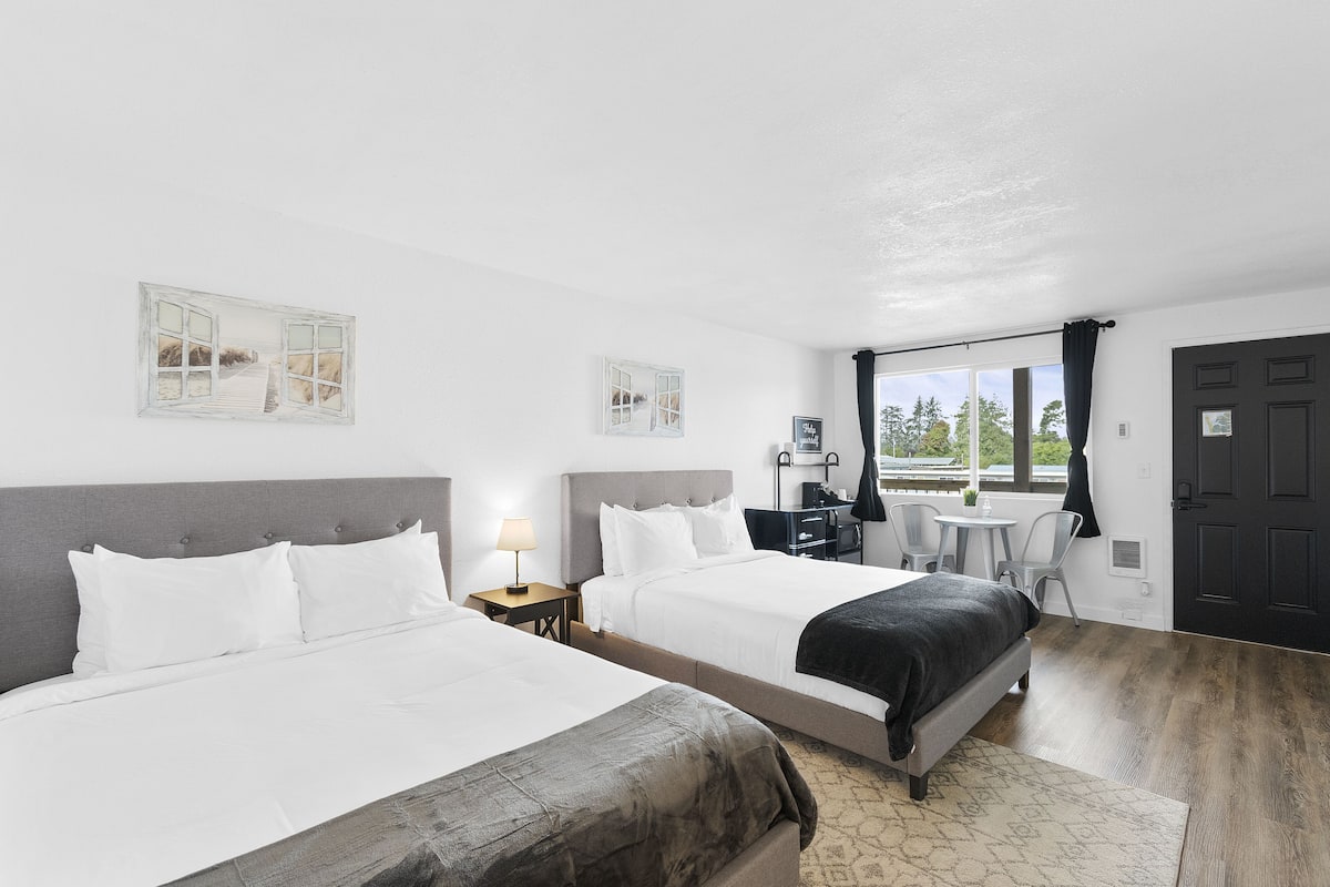 Quarto de hotel com duas camas, uma escrivaninha e uma cadeira.