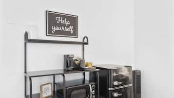 A kitchenette with a microwave, coffee maker, and a sign that says "Help yourself."