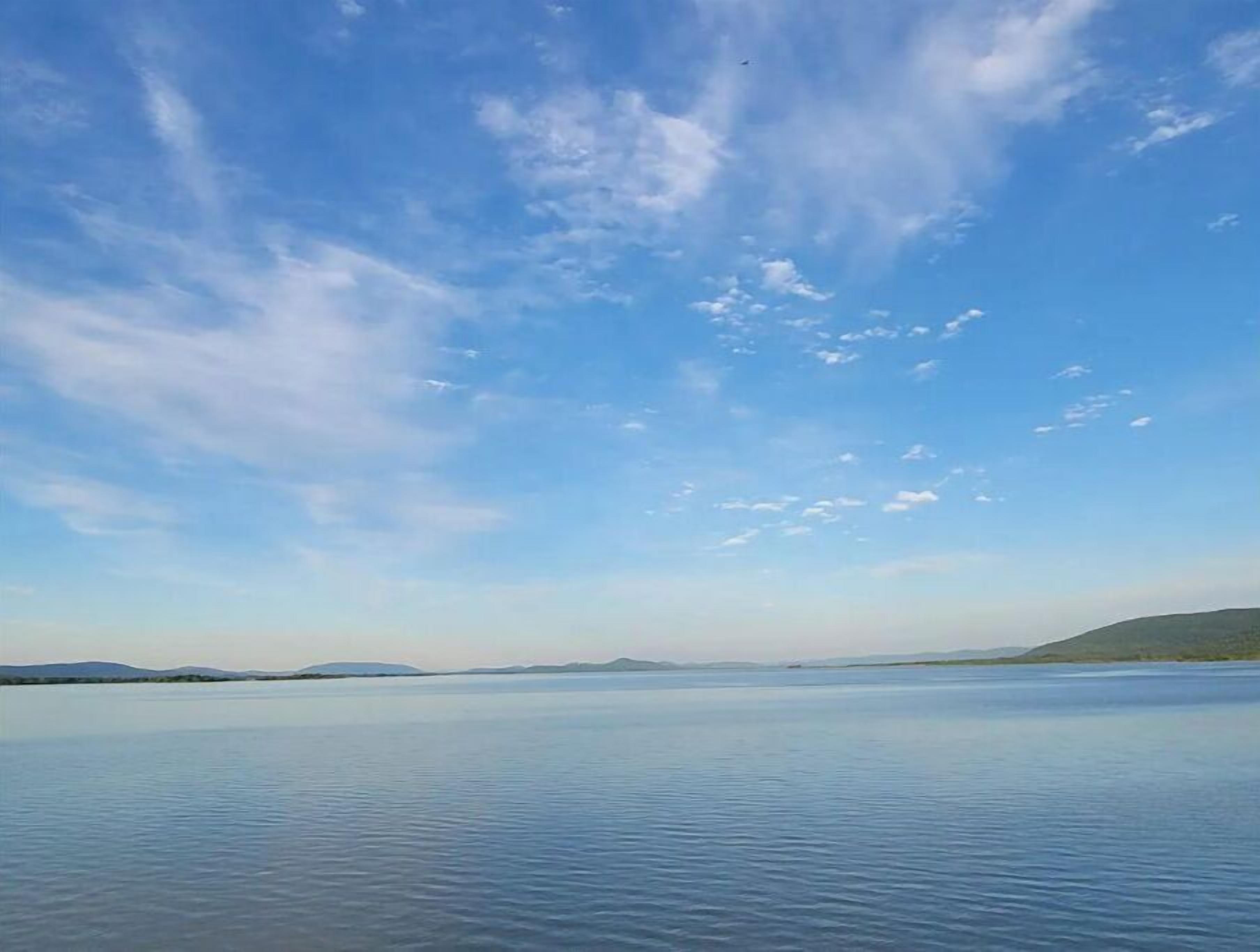 A calm lake with a clear sky and distant hills.