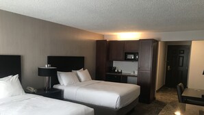 Een hotelkamer met twee bedden, een bureau, een magnetron en een kleine kitchenette.