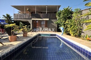 A modern house with a swimming pool, surrounded by potted plants and a clear blue sky. - Pousada Casa da Tatá (Búzios)