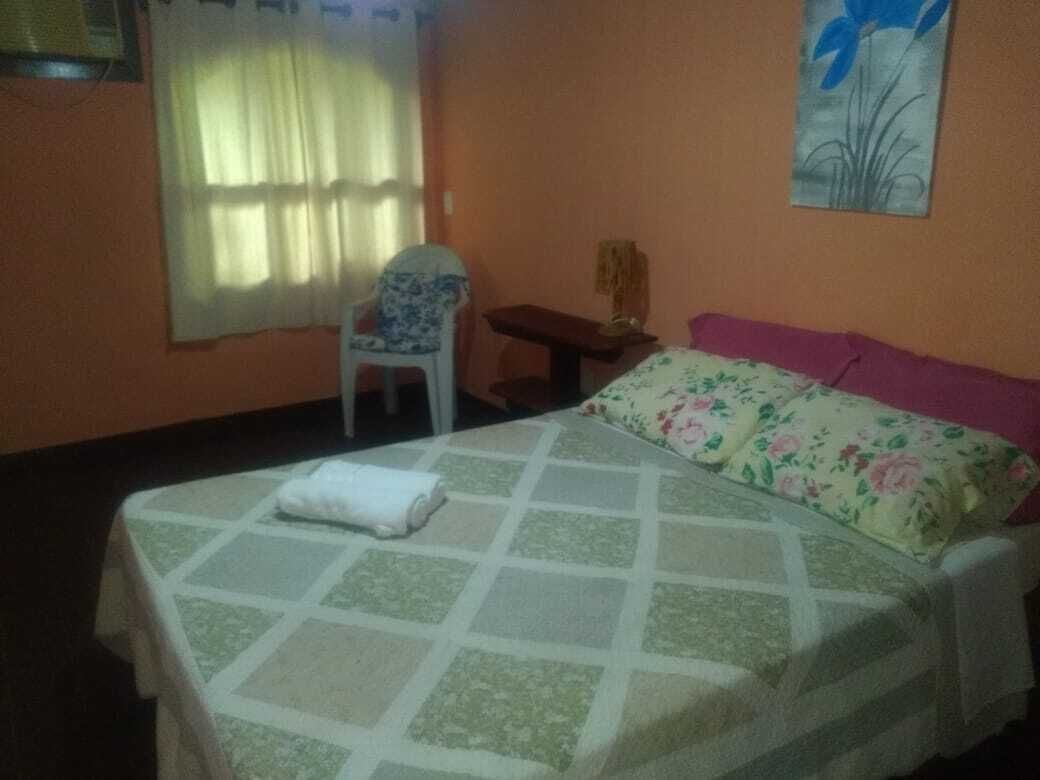 A hotel room with a bed, a chair, a small table, and a window with curtains.