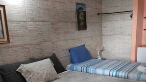 A bedroom with two beds, one with a striped bedspread and the other with a floral one. There are towels on the bed and a lamp on the side. - Pousada Casa da Tatá (Búzios)