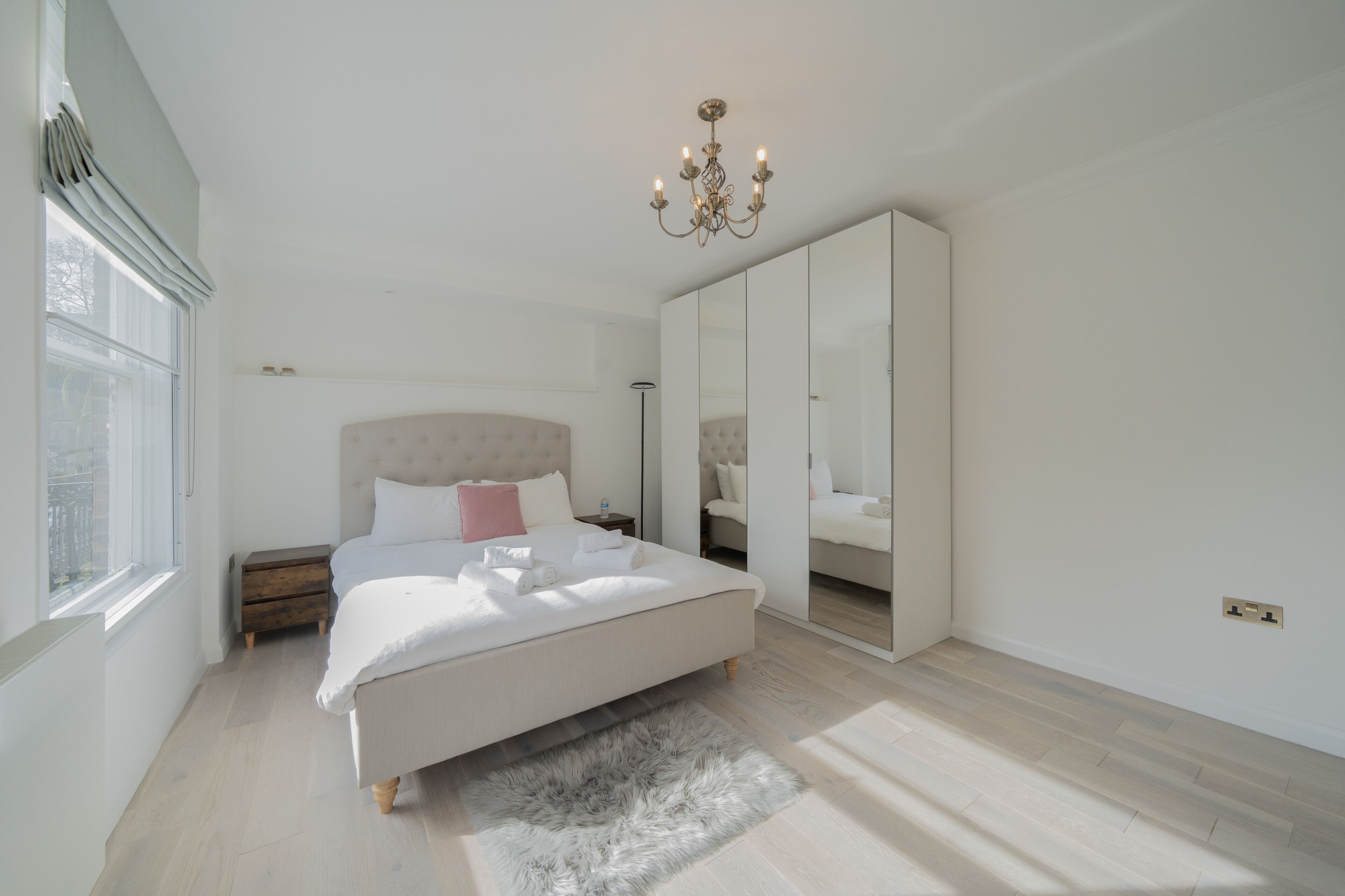 Une chambre à coucher avec un grand lit, un lustre, une armoire et une fenêtre.