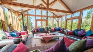 A spacious room with wooden beams, large windows, and colorful cushions. - Oakhouse - sleeps 16 guests  in 5 bedrooms (Preston)