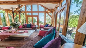 A spacious room with large windows, wooden beams, and a variety of seating options including sofas and a table. - Oakhouse - sleeps 16 guests  in 5 bedrooms (Preston)