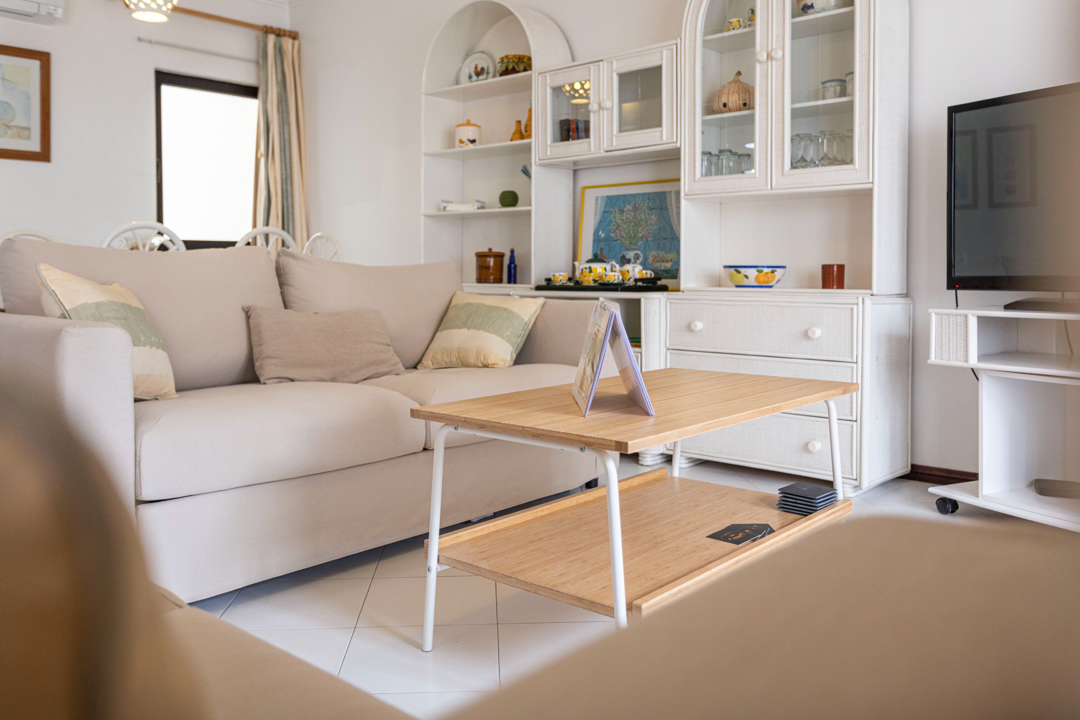 A modern living room with a sofa, a wooden coffee table, and a television.