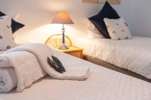 Ein ordentlich bezogenes Bett mit einem gefalteten Handtuch, einer Haarbürste, einer Nachttischlampe und zwei Kopfkissen mit Sternenmuster.