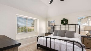 A bedroom with a bed, a nightstand, a window with blinds, a ceiling fan, and a view of the outside. - Home Pool 15 Minutes from DFW Airport (Flower Mound)