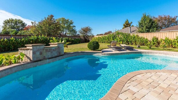 A rectangular swimming pool with a brick border and a paved deck area. - Home Pool 15 Minutes from DFW Airport (Flower Mound)