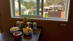 Une table avec des collations et des boissons, une fenêtre donnant sur un jardin, et un panneau avec des instructions.