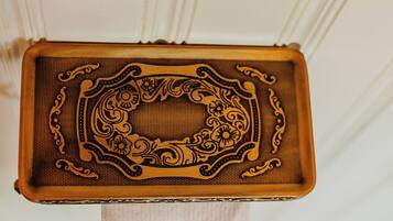 A rectangular tray with ornate floral patterns and a central button, placed on a white stand.