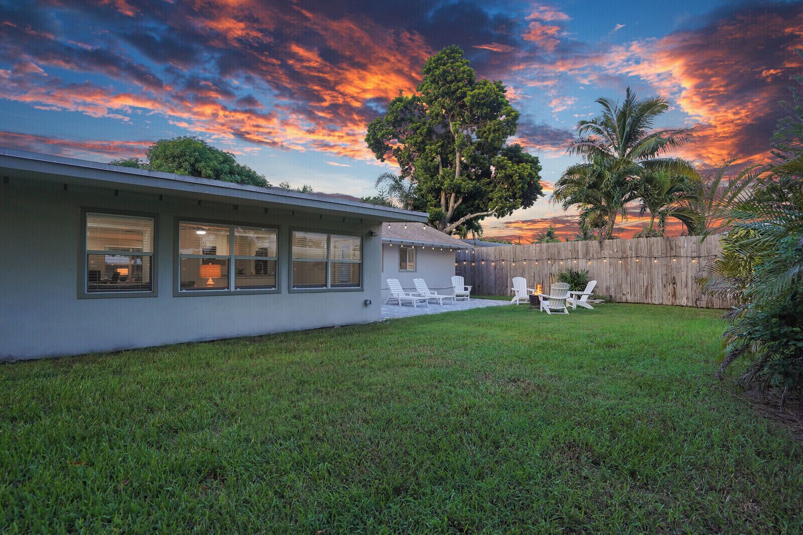 A residential house with a backyard patio, outdoor seating, and a wooden fence.