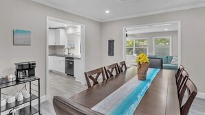 A modern kitchen with white cabinets, a coffee machine, and a dining area with a wooden table and chairs.