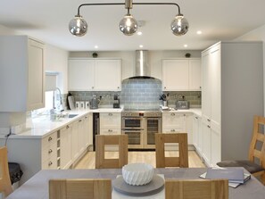 Una cocina moderna con armarios blancos, electrodomésticos de acero inoxidable y una isla central con asientos.