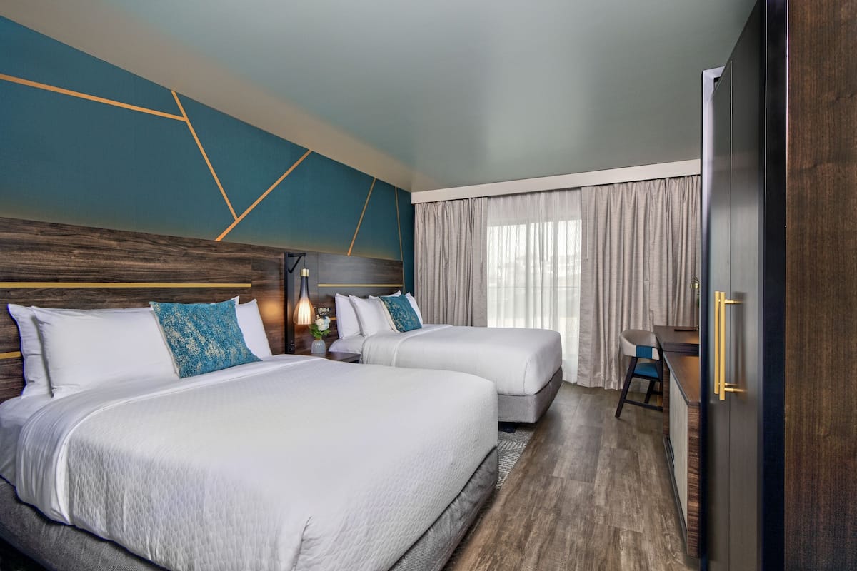 A hotel room with two beds, a desk, and a wardrobe.