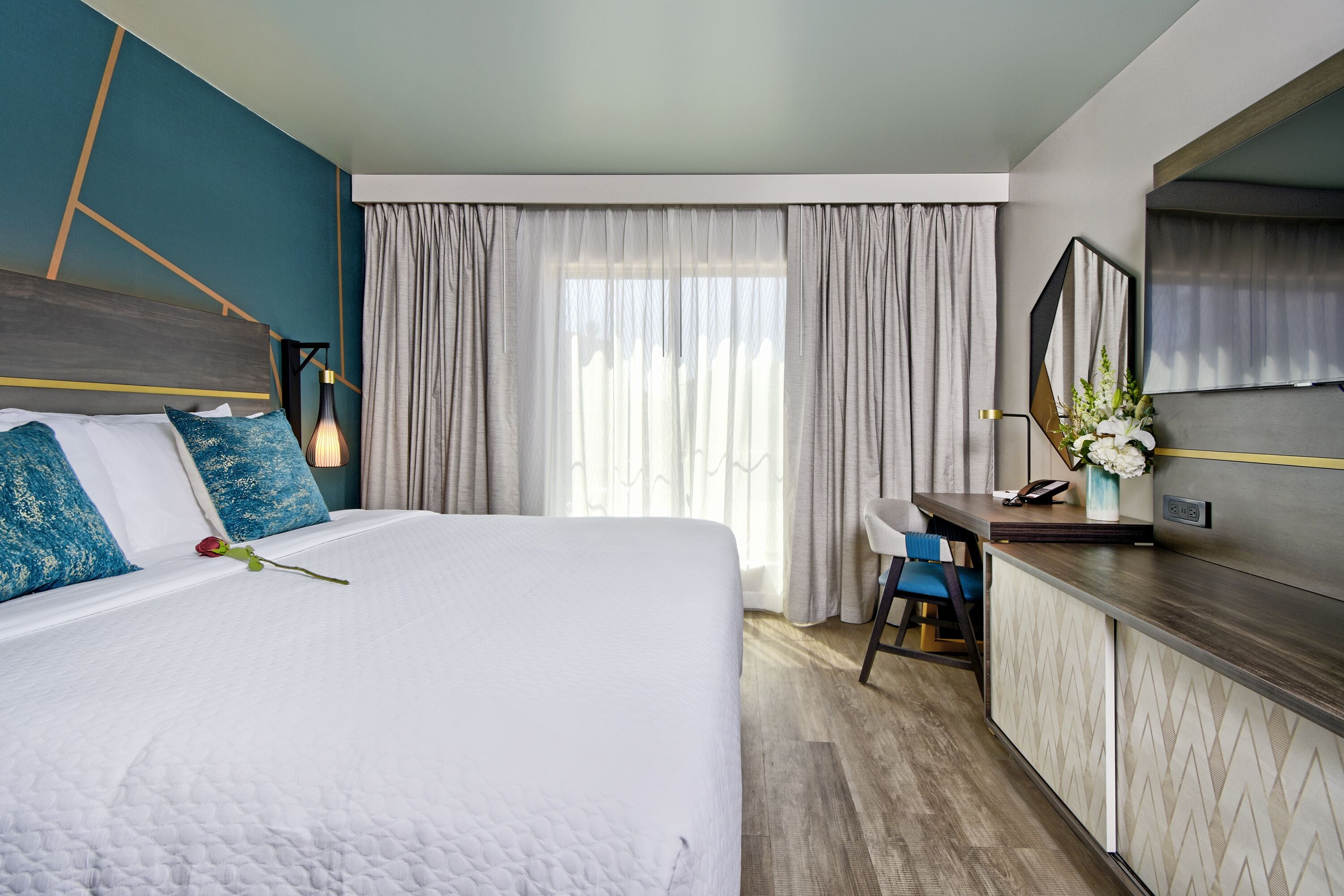 Una camera d'albergo moderna con un letto grande, una scrivania e uno specchio.