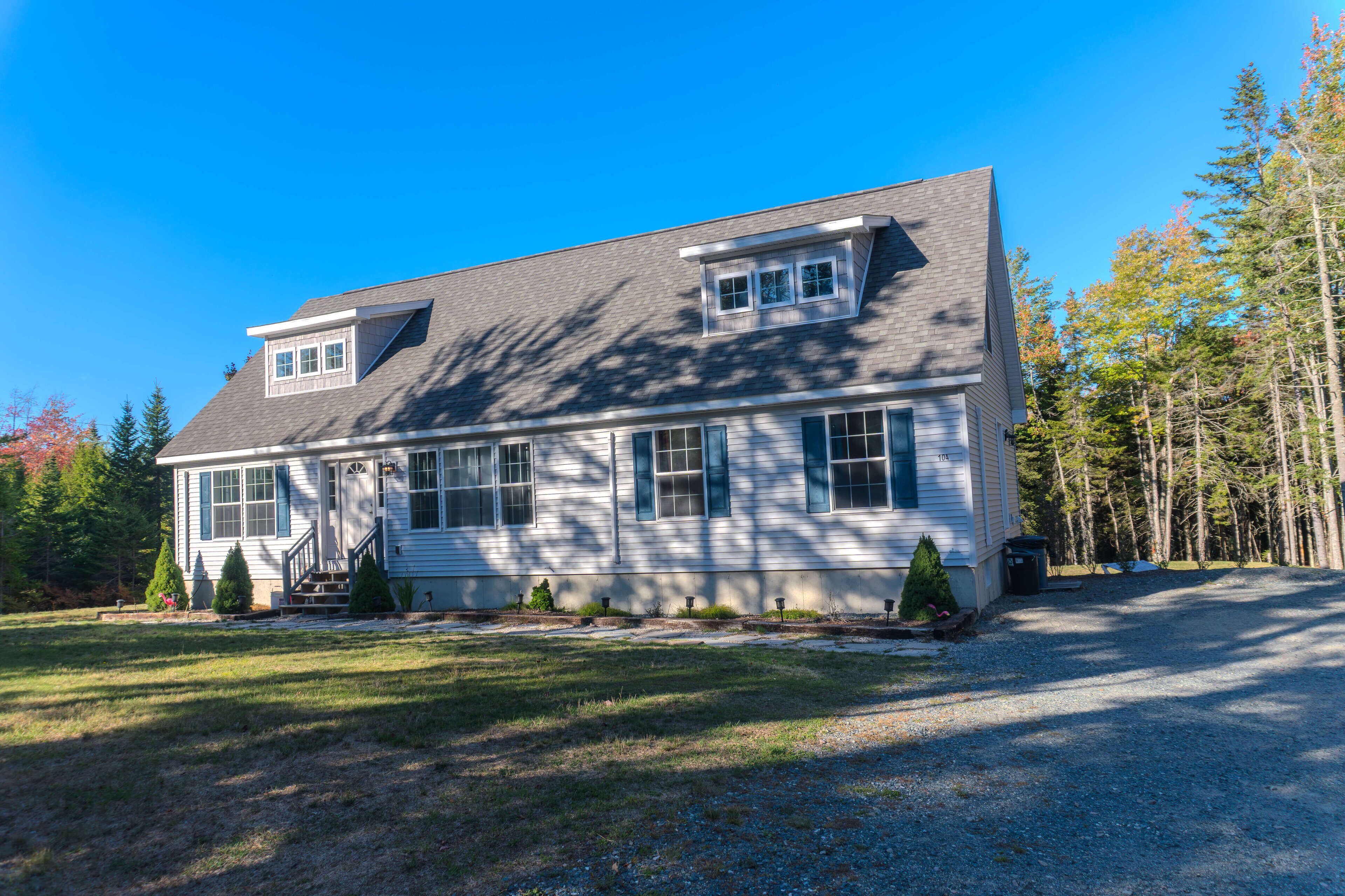 A two-story house with a sloped roof, a front porch, and a driveway leading to the entrance.