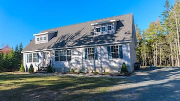 A two-story house with a sloped roof, a front porch, and a driveway leading to the entrance.