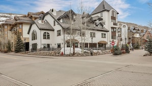A residential area with a row of houses featuring a mix of architectural styles, including a prominent house with a gabled roof and a stone foundation.