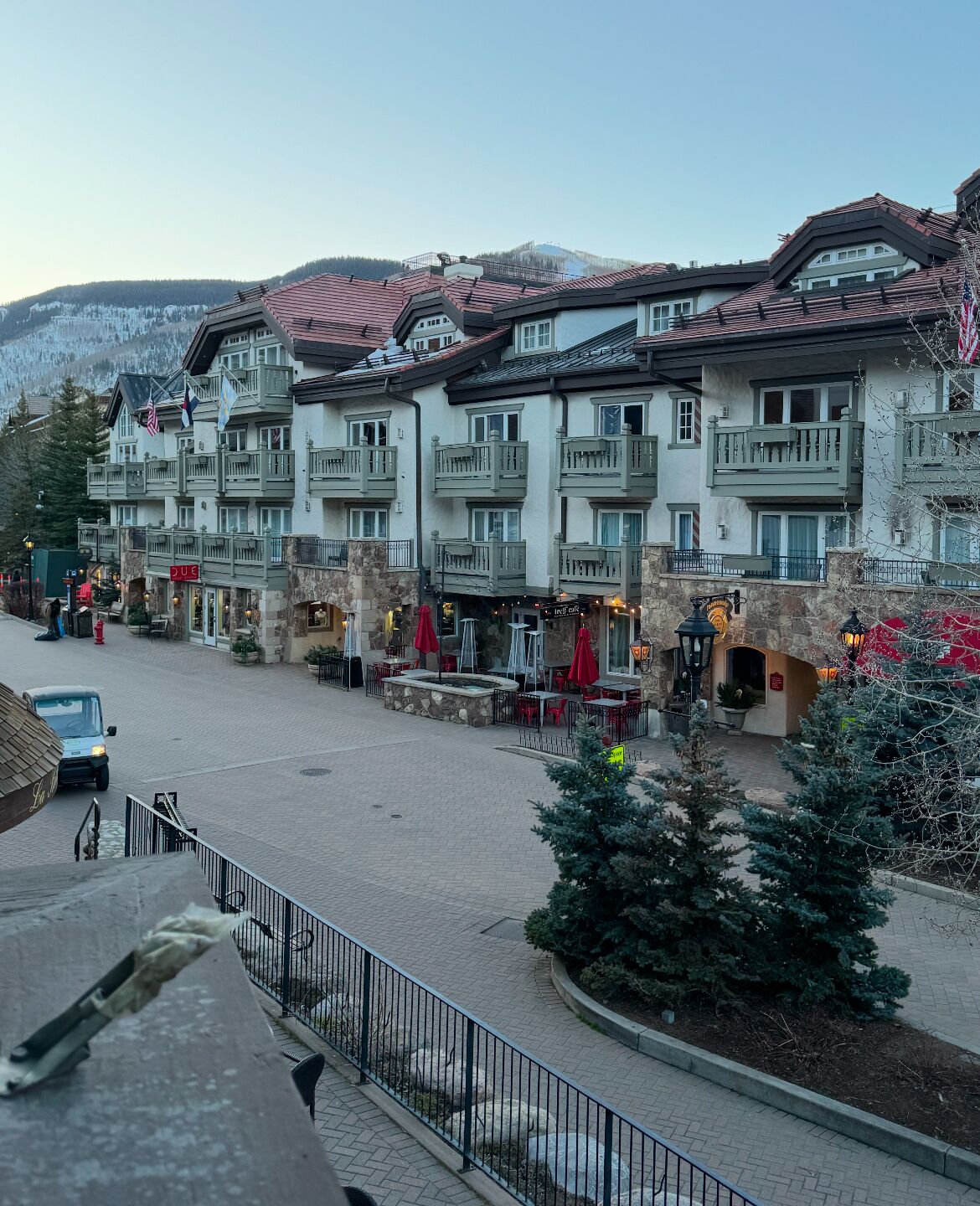A multi-story hotel with balconies, outdoor seating, and a stone facade.