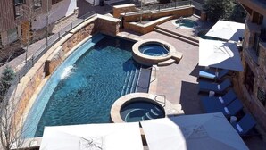 A rooftop pool area with multiple hot tubs and lounge chairs.