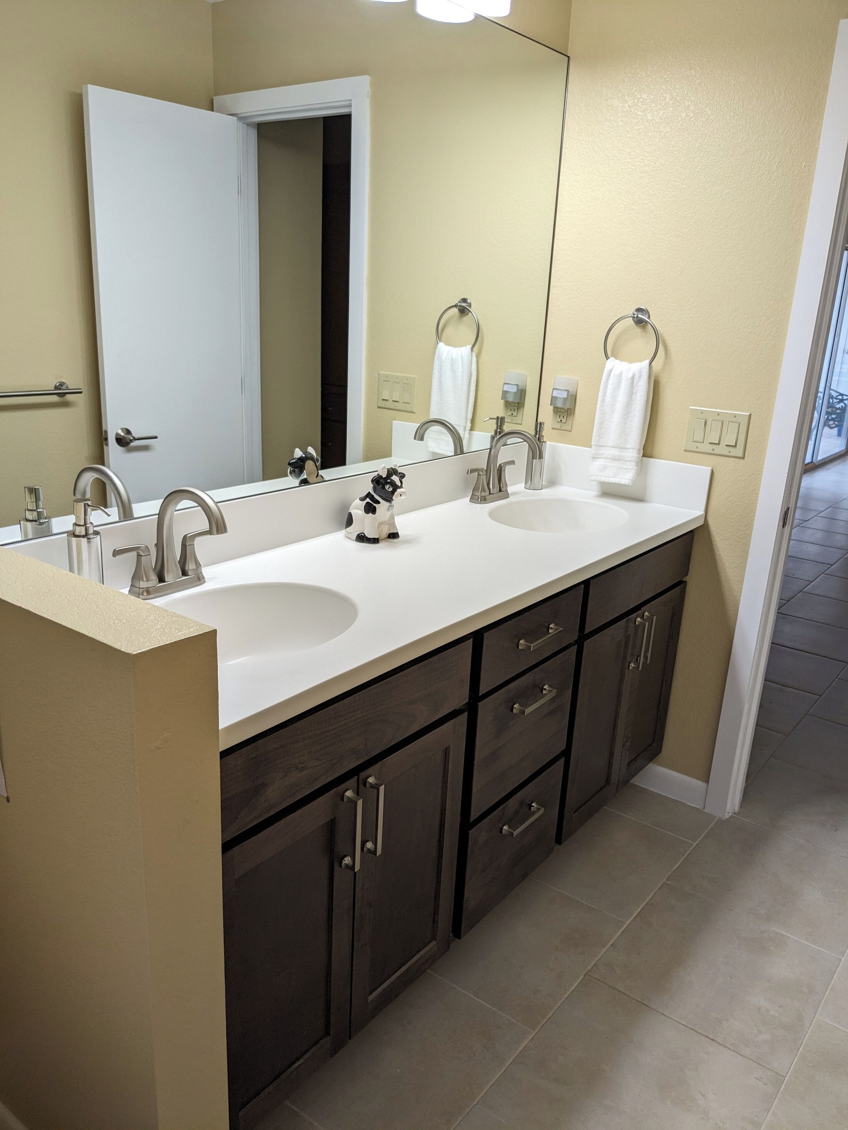 A bathroom with two sinks, a large mirror, and dark wooden cabinets.
