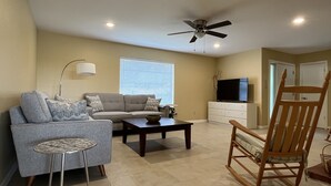 Una sala de estar con sofá, mesa de centro, mecedora y televisor.