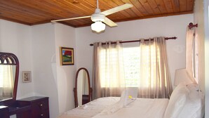 A bedroom with a bed, a ceiling fan, a dresser, a mirror, and a window with curtains. - La Casita de Cabrera by Cabrera Lodge (Nagua)
