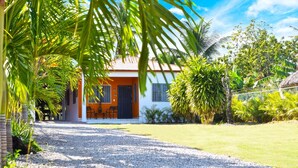 A house with a gravel driveway, surrounded by lush greenery and palm trees. - La Casita de Cabrera by Cabrera Lodge (Nagua)