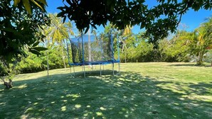 A trampoline in a grassy area with trees and a clear sky. - La Casita de Cabrera by Cabrera Lodge (Nagua)