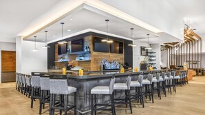 A modern bar area with a long counter, multiple bar stools, and a variety of bottles and glasses. - Hyatt Place Houston Medical Center (Houston)
