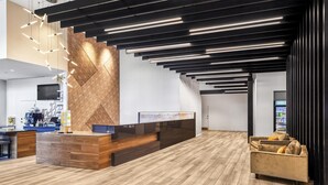 A modern reception area with a wooden reception desk, a coffee machine, and a seating area with a sofa and armchairs. - Hyatt Place Houston Medical Center (Houston)