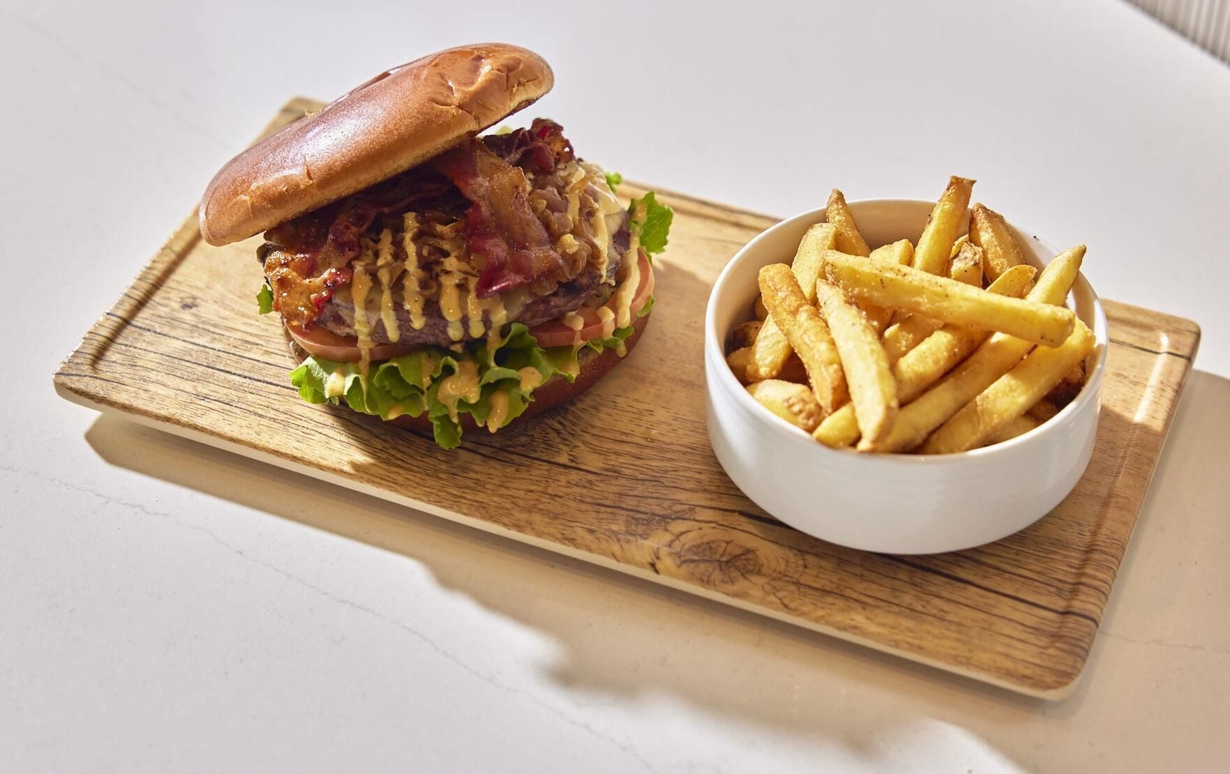 Un sandwich accompagné de frites, le tout servi sur une planche en bois.