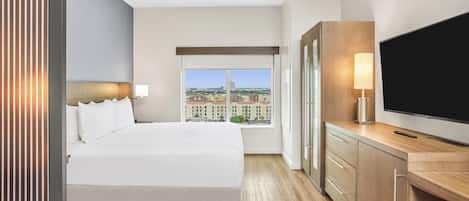 Habitación de hotel con una cama grande, televisión, escritorio y ventana con vistas a la ciudad.