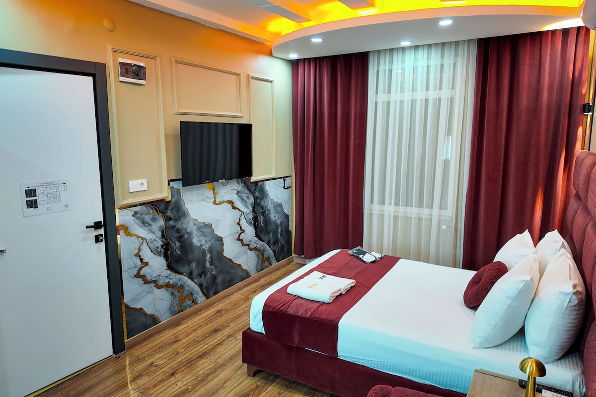 Habitación de hotel con cama, cortinas, ventana, puerta y aire acondicionado de pared.